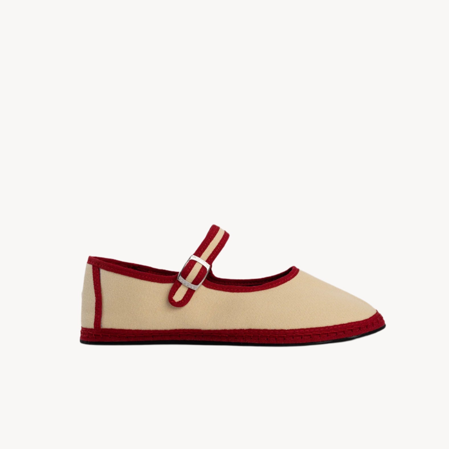 Beige shoe with red trim and buckle on a light gray background