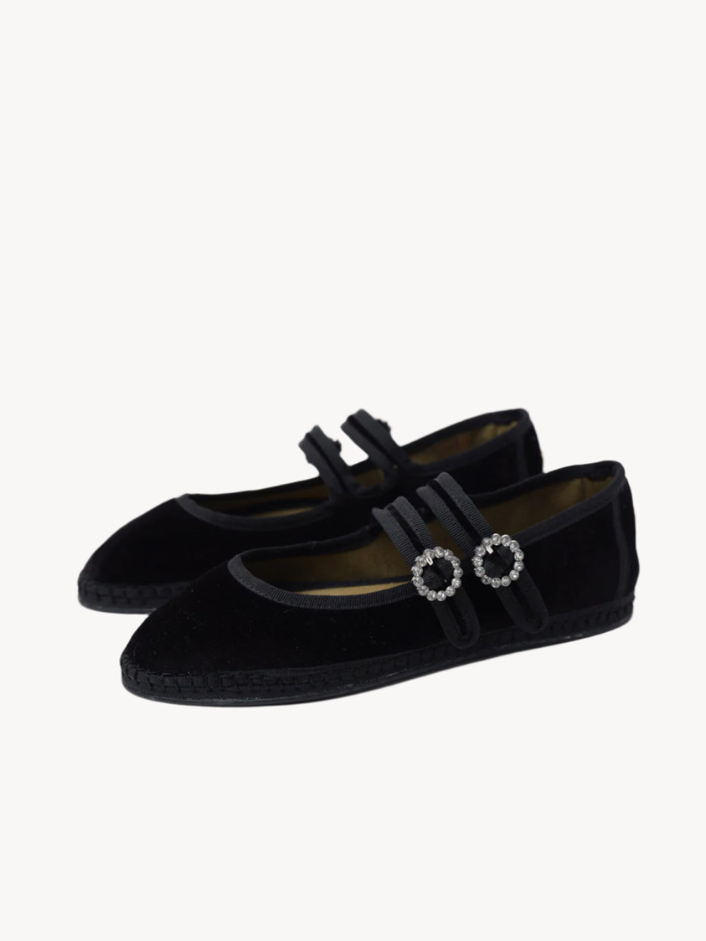 Black velvet shoes with decorative straps on a light background