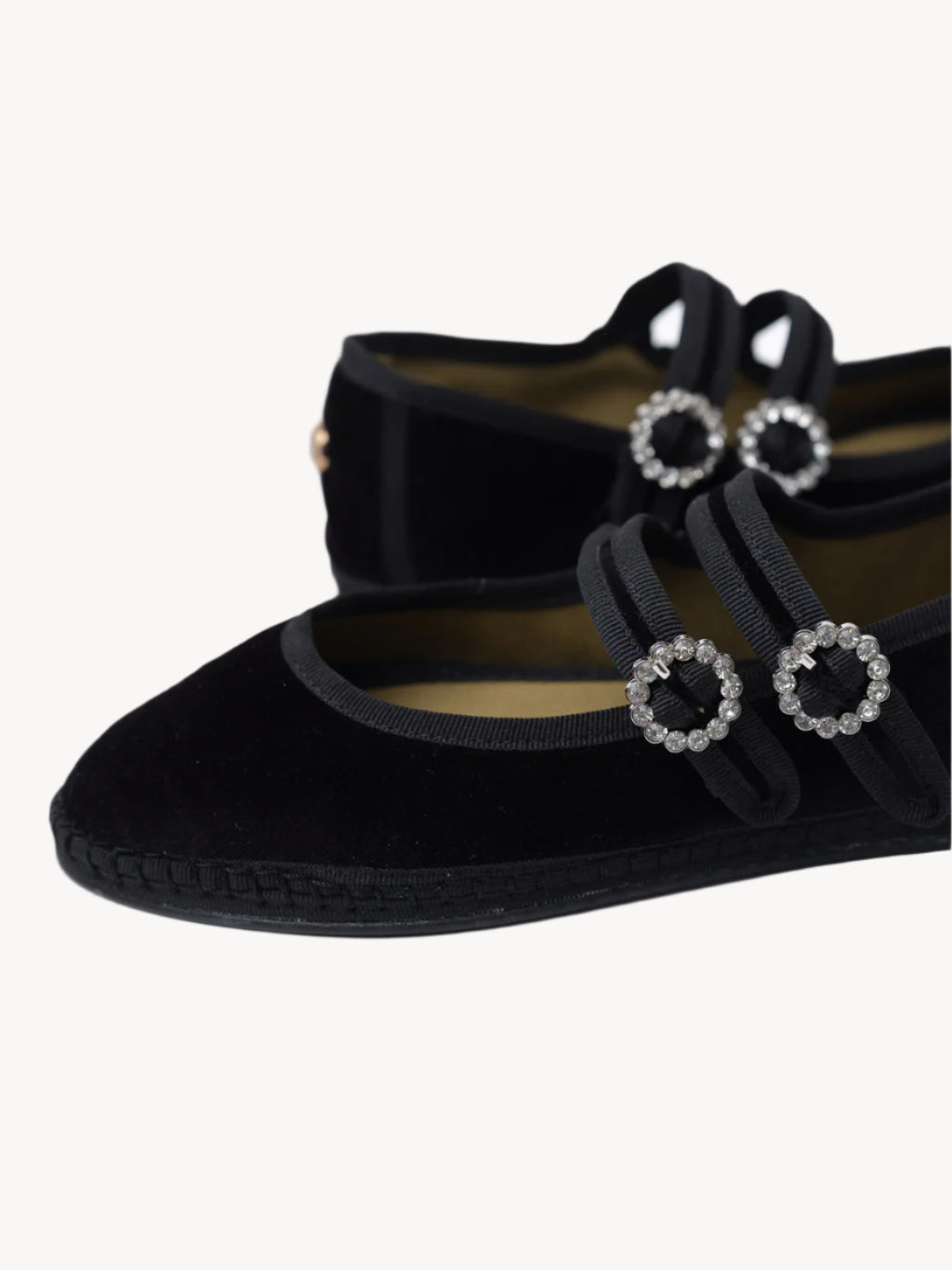 Black velvet shoes with decorative buckles on a light background