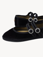 Black velvet shoes with decorative buckles on a light background