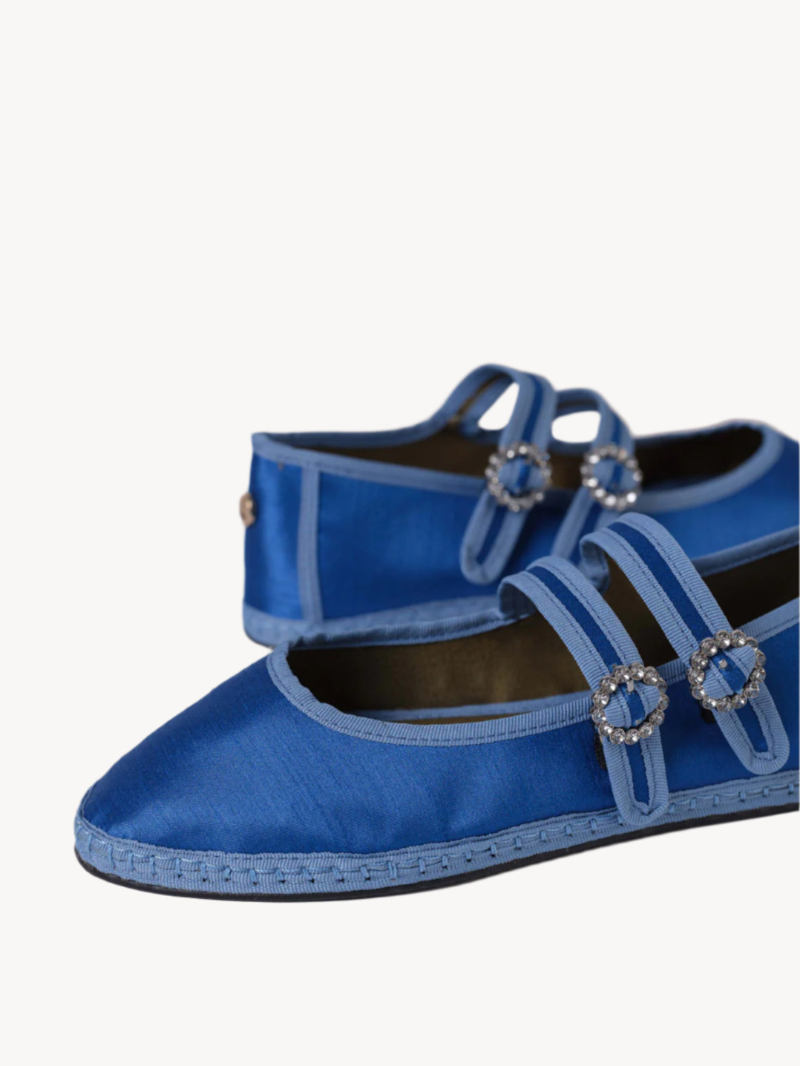 Blue satin shoes with decorative straps on a light background