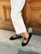 Person wearing black flats with white pants stepping onto a stone surface.