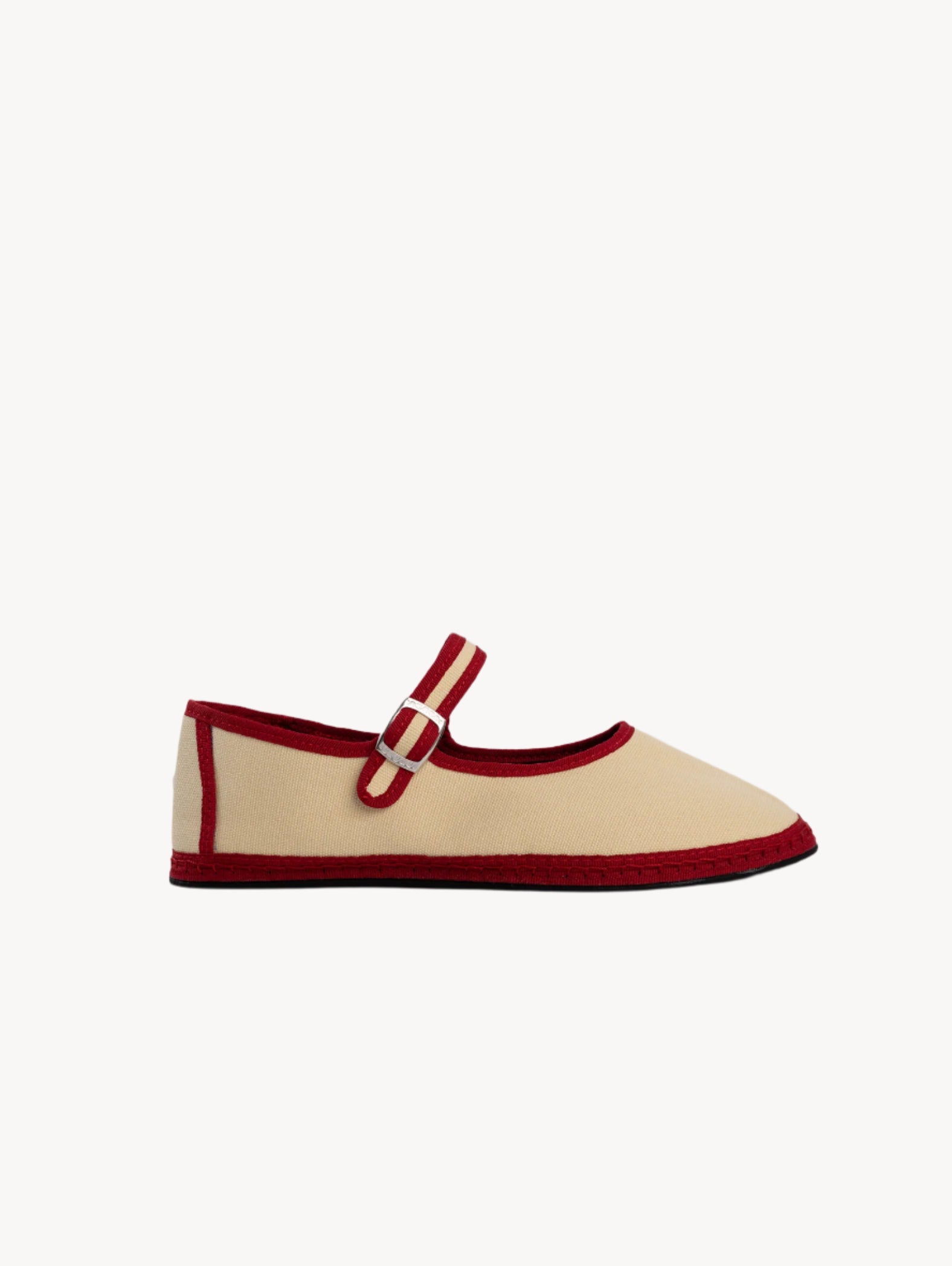 Beige shoe with red trim and buckle on a light gray background