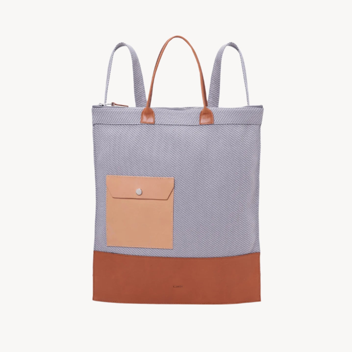 A backpack with camel brown and gray colors, featuring a oceanic recycled plastic textured fabric, a main compartment and an interior pocket, with leather handles on the top and adjustable back straps.