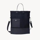 Black crossbody bag with a shoulder strap on a light gray background